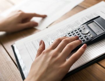 Closeup photo of woman's hands counting on calculator
